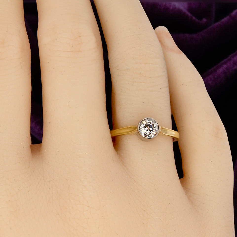 Gold ring with a diamond on a hand against a purple fabric background