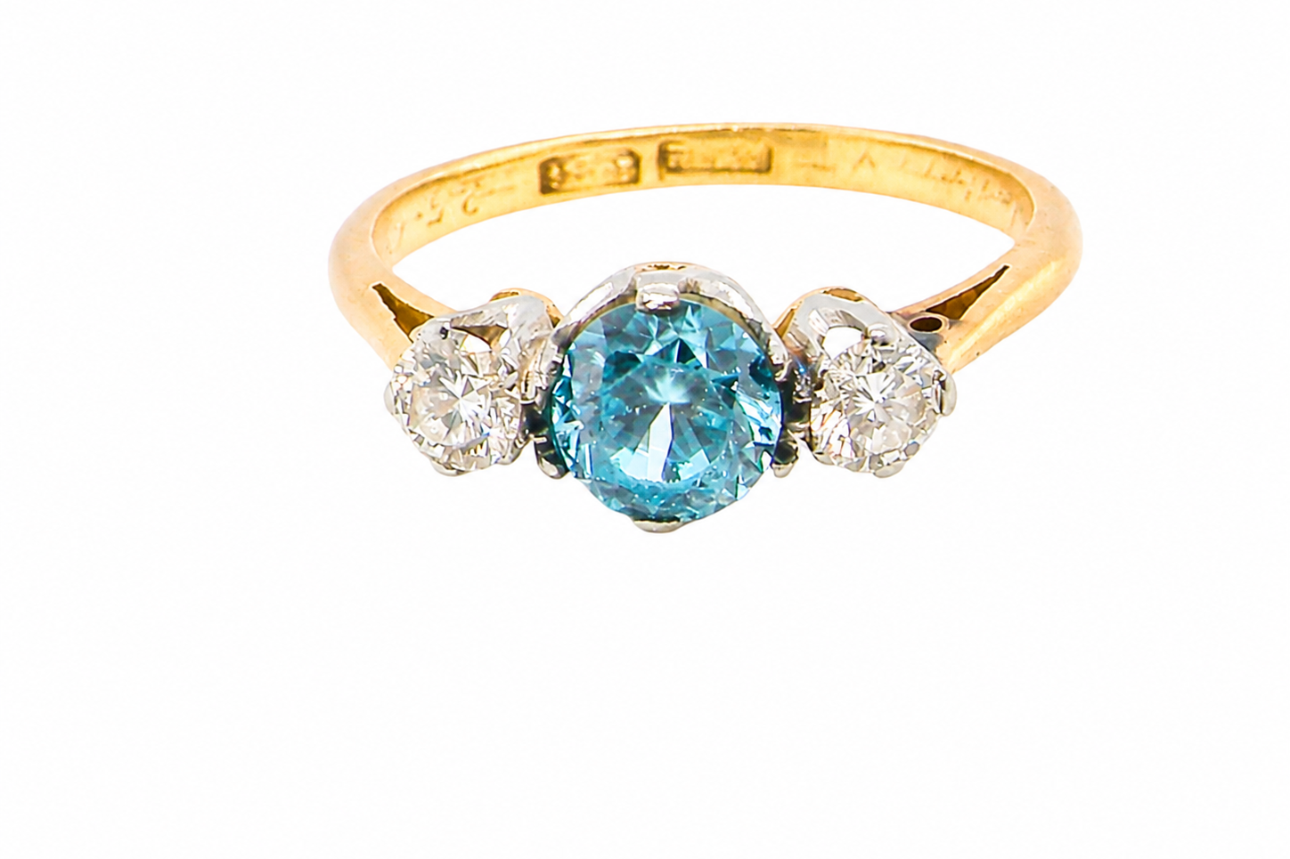 A vintage three stone ring. Centre stone, a round 5.8mm natural blue zircon.
To each side an old brilliant cut white diamond 4mm round (est 0.25 carats).