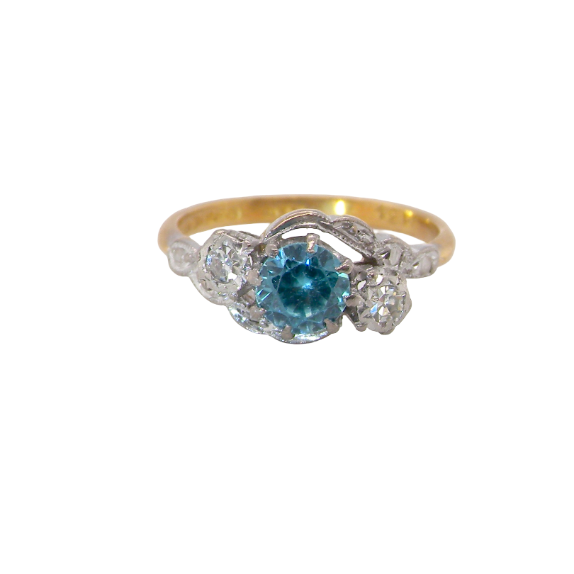 A vintage three stone ring, cross over style and features a round 6mm natural blue zircon centre stone
