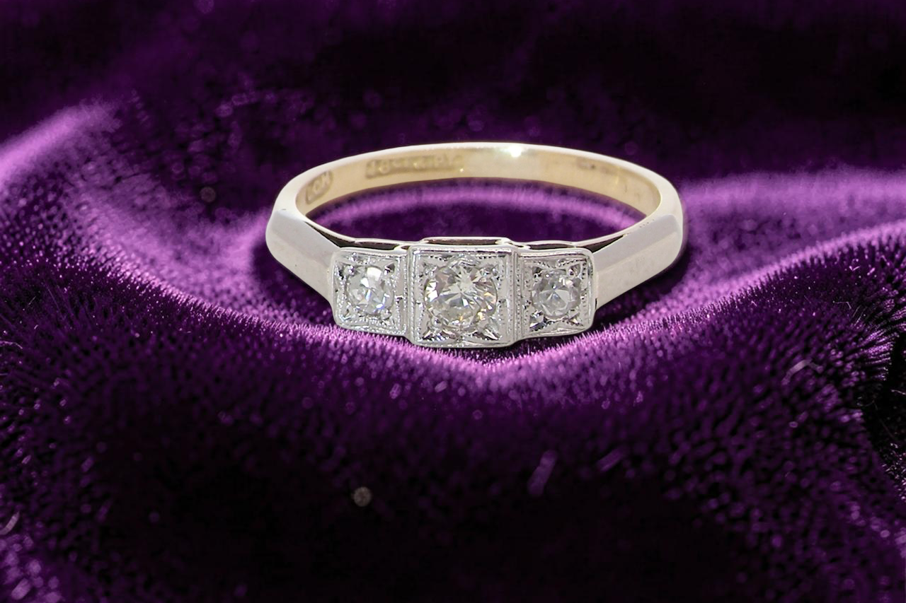 A vintage trilogy ring. Set with three old brilliant cut white diamonds, centre 3mm and each side a 2.4mm diamond. Total estimated at 0.20 carats,