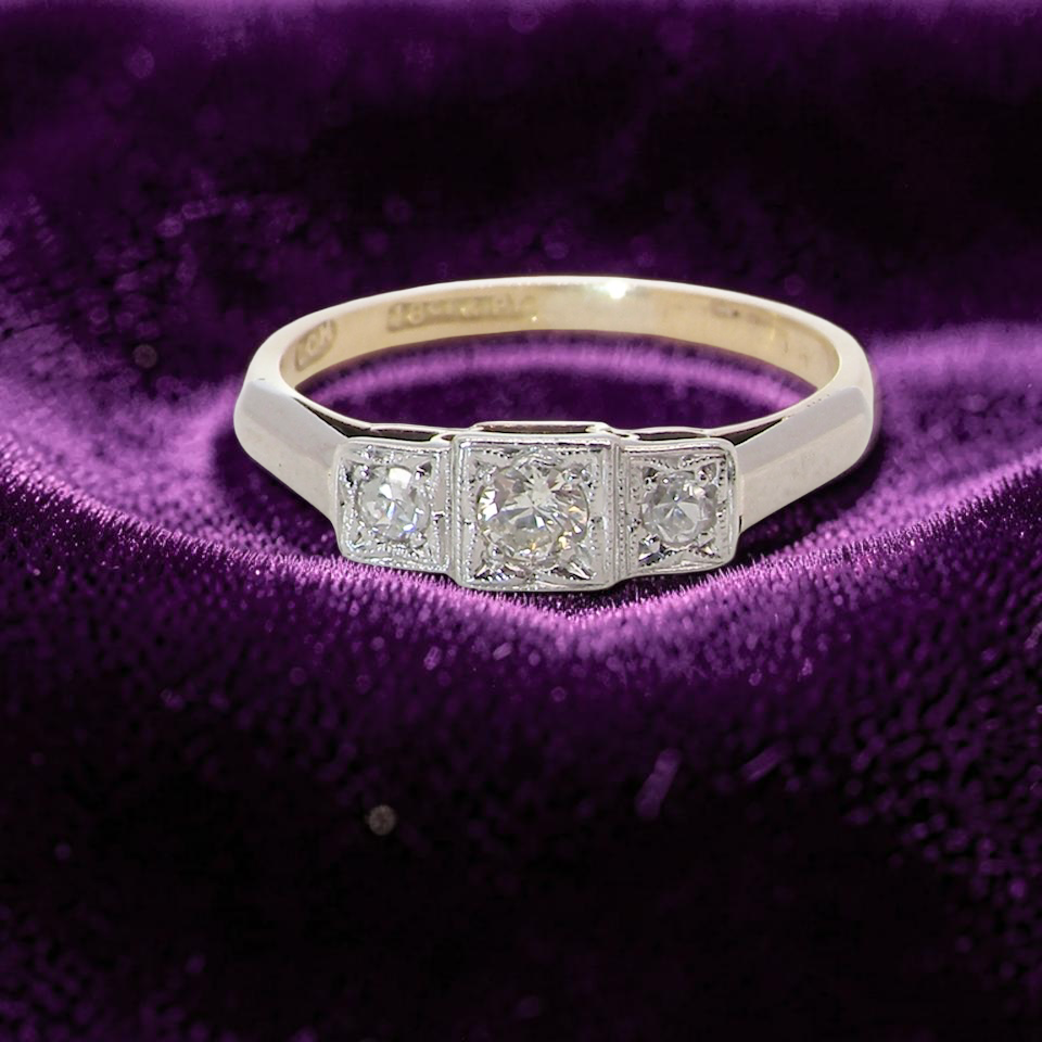A vintage trilogy ring. Set with three old brilliant cut white diamonds, centre 3mm and each side a 2.4mm diamond. Total estimated at 0.20 carats,