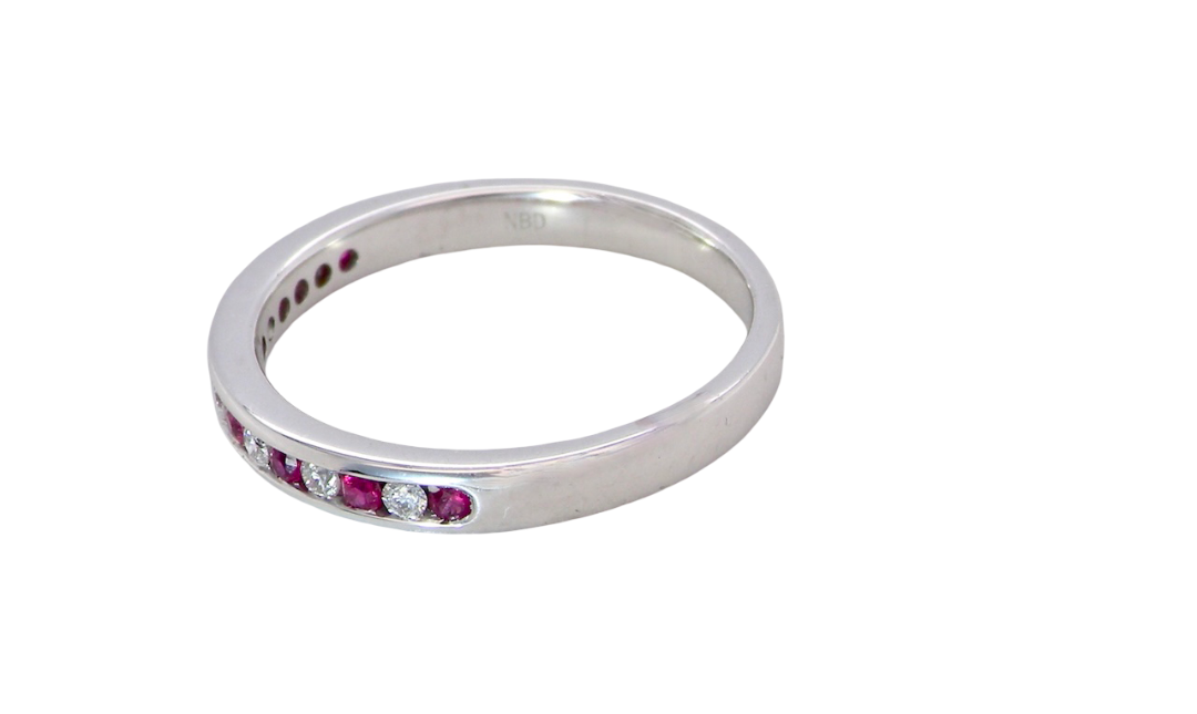 A white gold half hoop eternity ring. Set with seven round rubies and six brilliant cut white diamonds side