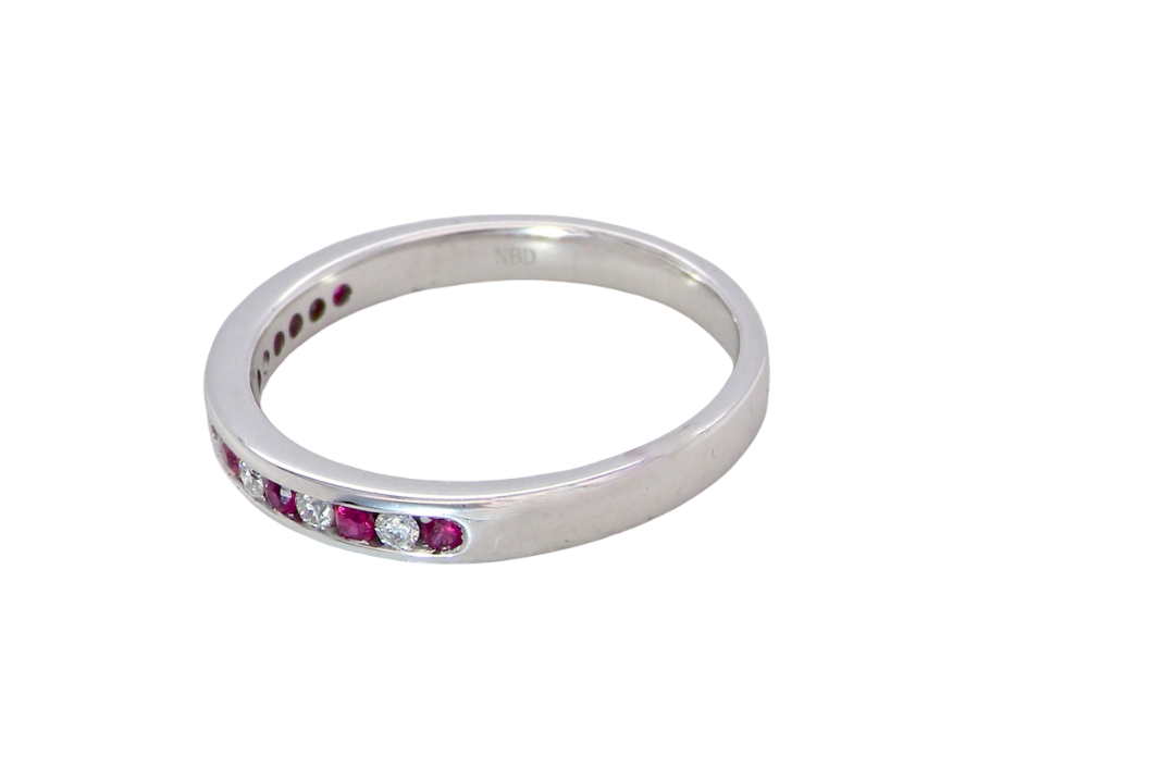 A white gold half hoop eternity ring. Set with seven round rubies and six brilliant cut white diamonds side