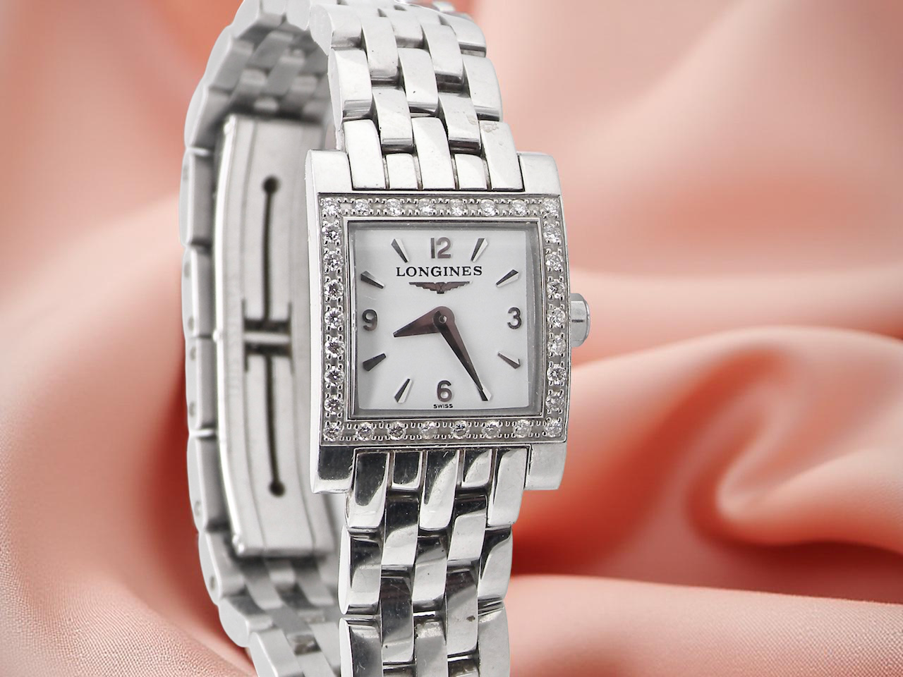 Silver Longines watch on a soft pink background