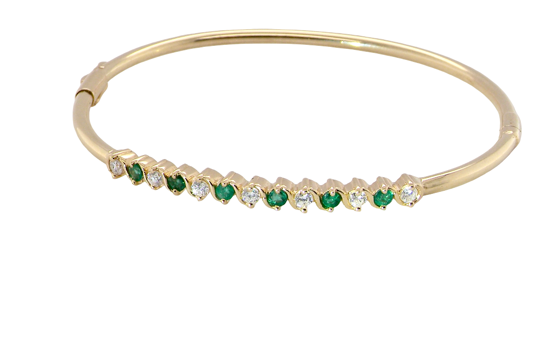 A yellow gold bangle. Features alternate emeralds and diamonds. Six 2.7mm emeralds and seven brilliant cut white diamonds, each 2.7mm (total diamond total 0.50 carats)