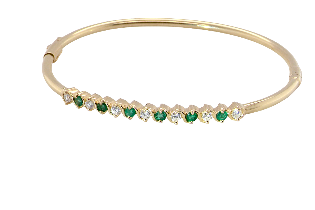 A yellow gold bangle. Features alternate emeralds and diamonds. Six 2.7mm emeralds and seven brilliant cut white diamonds, each 2.7mm (total diamond total 0.50 carats)