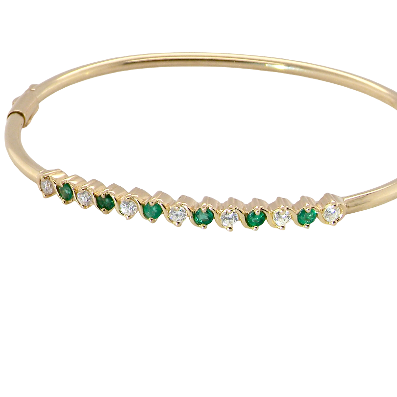 A yellow gold bangle. Features alternate emeralds and diamonds. Six 2.7mm emeralds and seven brilliant cut white diamonds, each 2.7mm (total diamond total 0.50 carats)