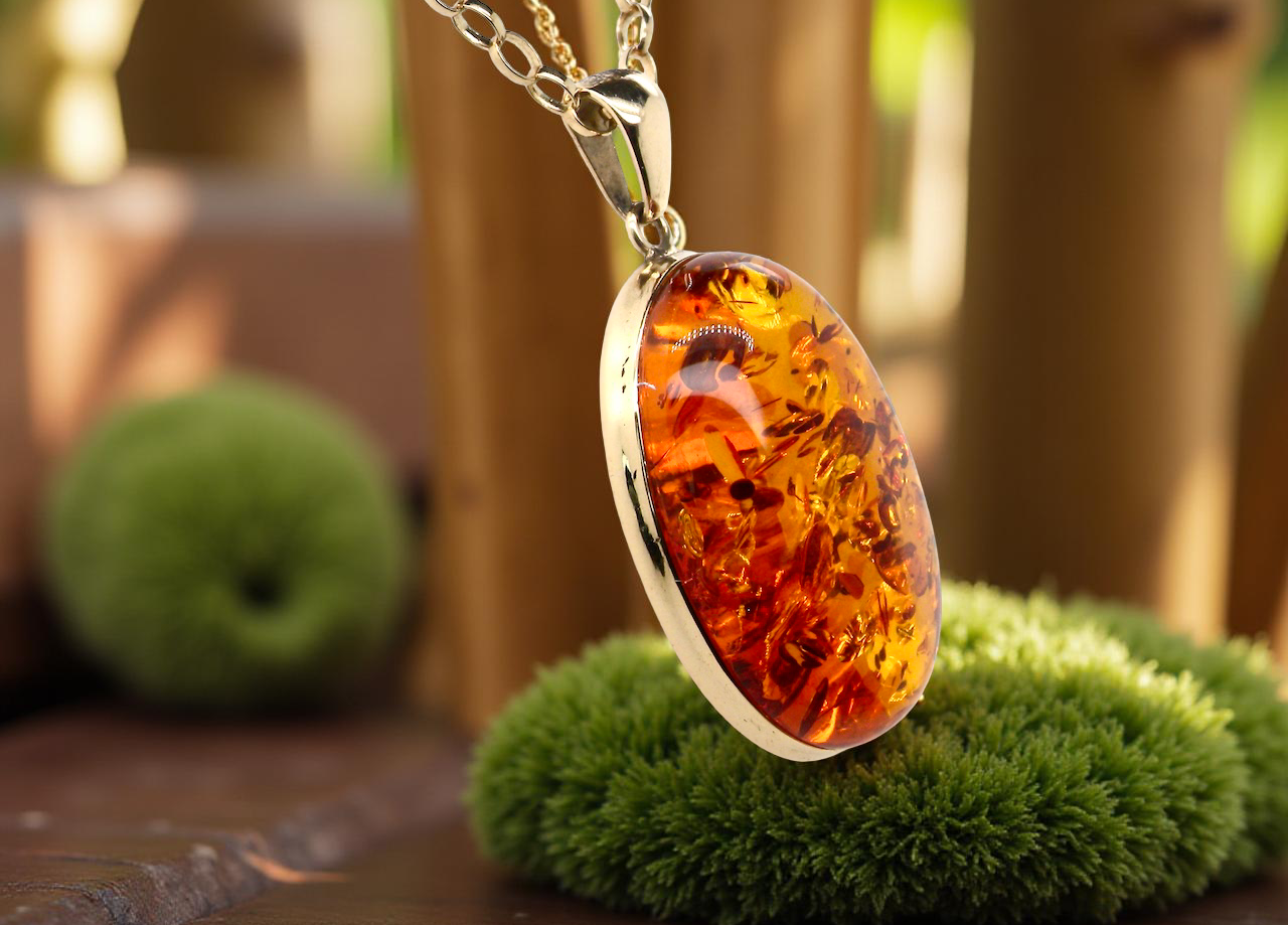 Amber pendant necklace on a stand with a blurred natural background