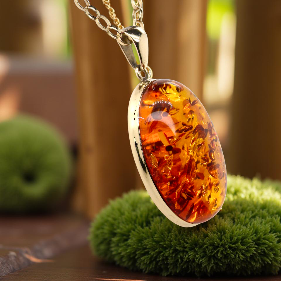Amber pendant necklace on a stand with a blurred natural background