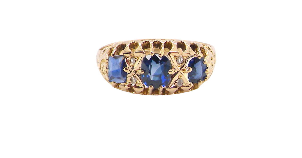 An 18 carat gold antique boat shaped ring. Features three oval to cushion cut sapphires, centre 6x5mm, each end 5x3mm. Mid to dark blue
