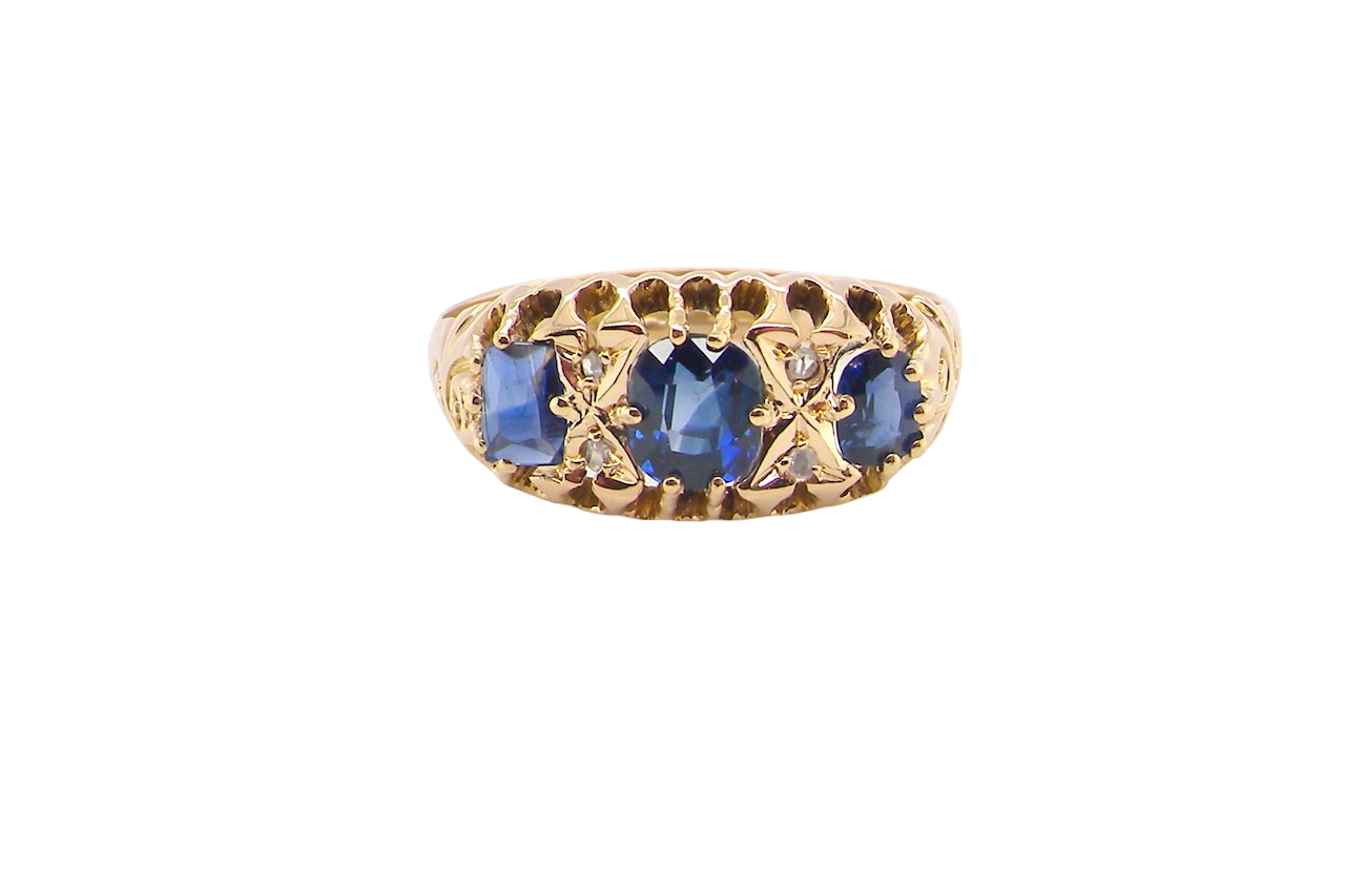 An 18 carat gold antique boat shaped ring. Features three oval to cushion cut sapphires, centre 6x5mm, each end 5x3mm. Mid to dark blue