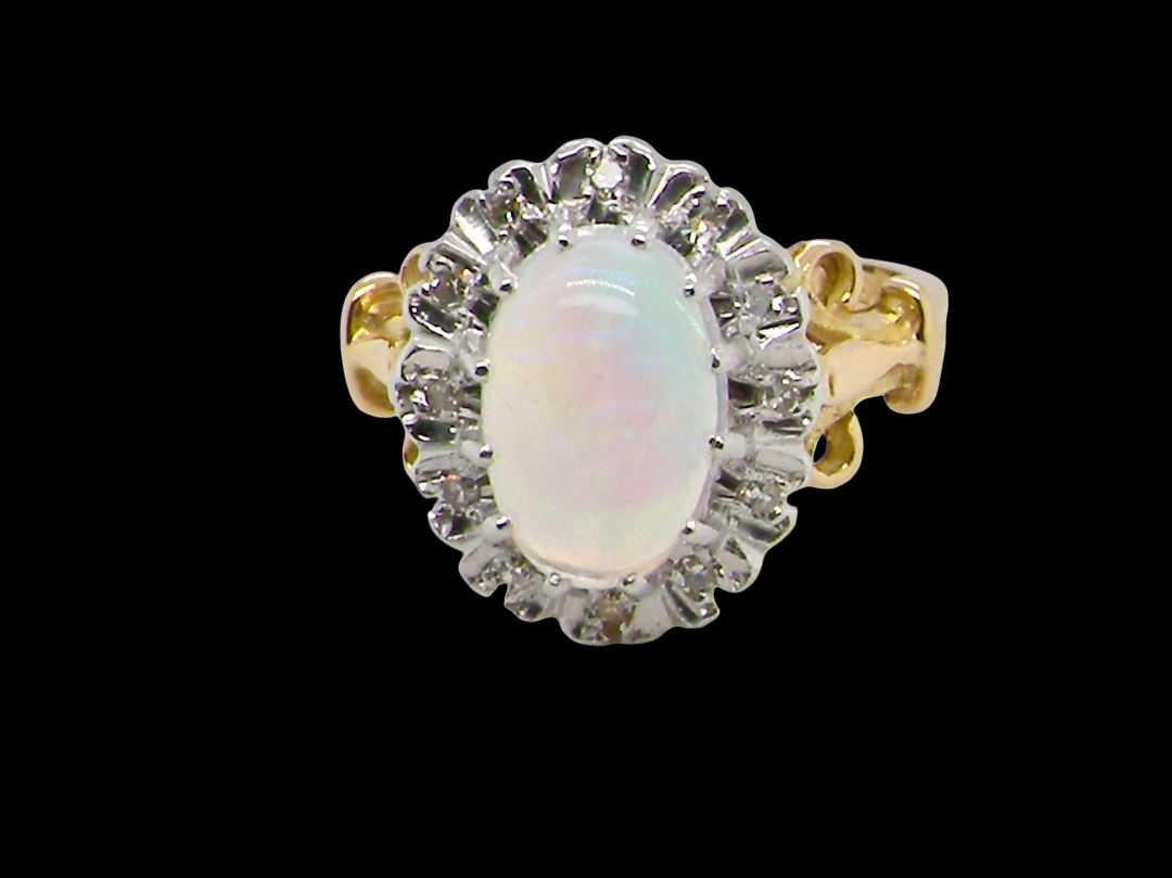 An 18 carat gold cluster ring. Features an oval opal centre stone with excellent play of colour with a predominance of watery purple and flashes of orange, and luminous green.