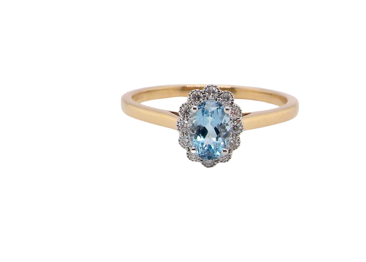 An 18 carat gold cluster ring. Set to the centre a lovely ice blue aquamarine 6x4mm,