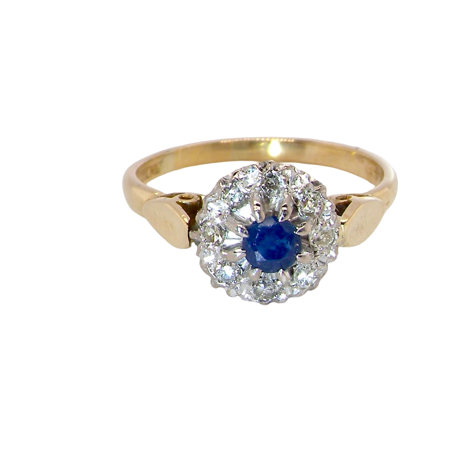 An 18 carat gold cluster ring, features to the centre a dark blue sapphire,. Claw set.