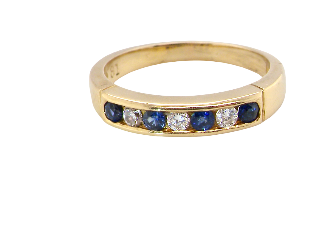 A yellow gold eternity-style ring featuring a row of round-cut blue sapphires and clear diamonds set in a channel, shown on a plain white background.