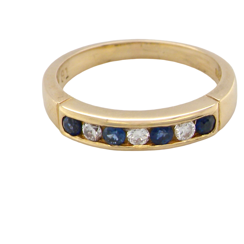 A yellow gold eternity ring featuring a row of round-cut dark blue sapphires and clear round diamonds set in a polished band, shown on a plain white background.