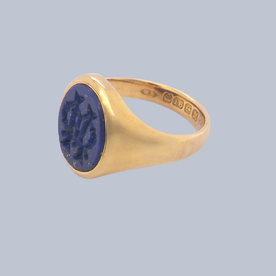 An 18 carat gold signet ring set with an oval lapis lazuli stone. This measures 12x9.5mm and has a carved intaglio seal engraved onto the stone.