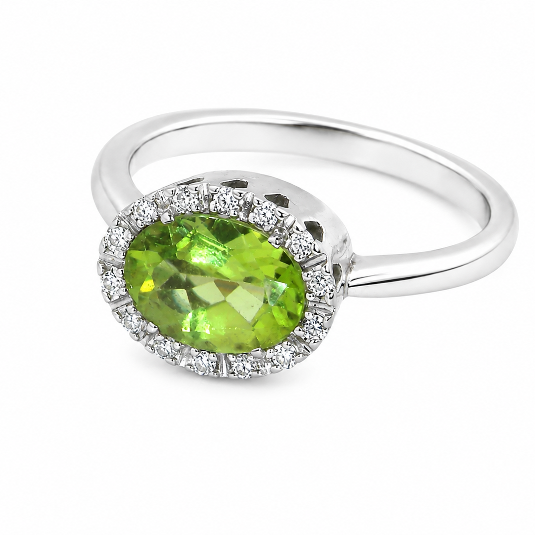An 18 carat white gold* cluster ring. Features and oval shaped peridot gemstone,