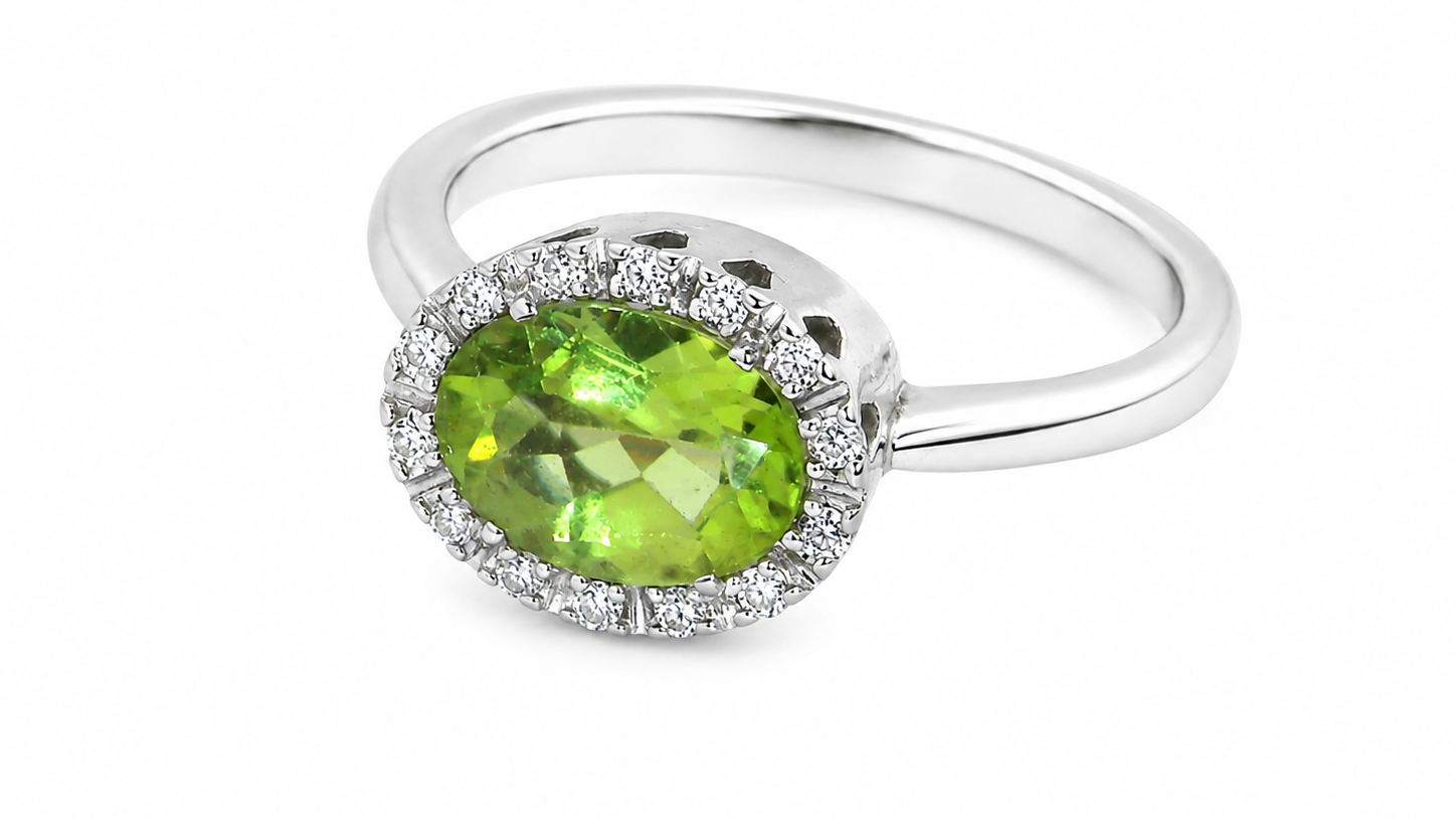 An 18 carat white gold* cluster ring. Features and oval shaped peridot gemstone,