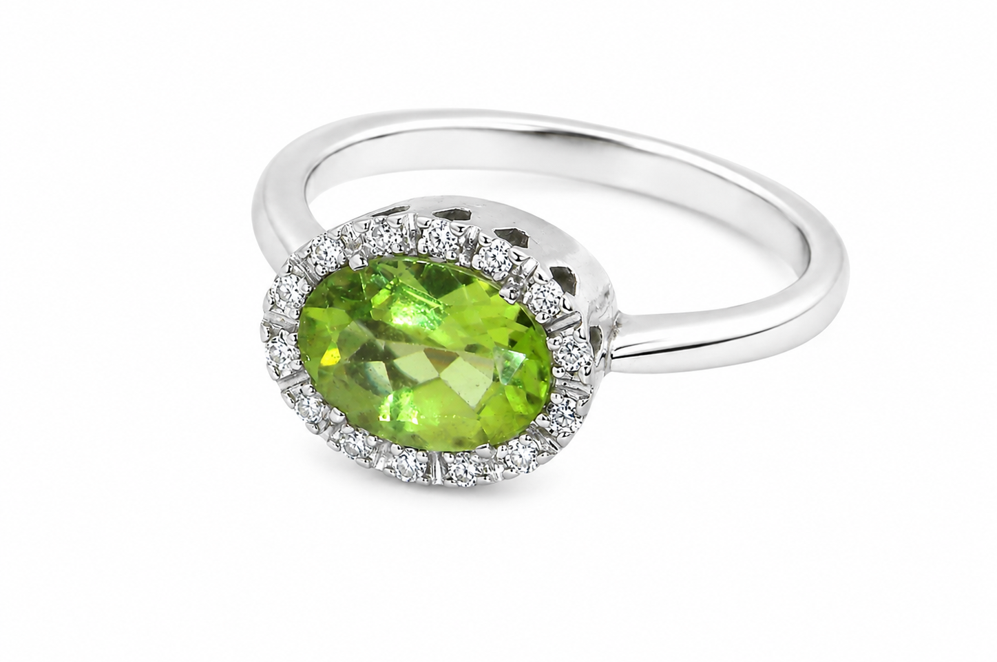 An 18 carat white gold* cluster ring. Features and oval shaped peridot gemstone,
