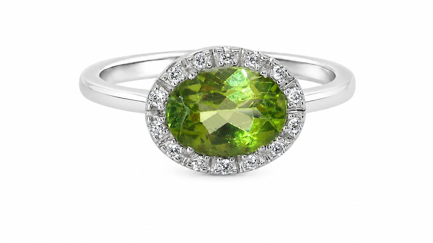 An 18 carat white gold* cluster ring. Features and oval shaped peridot gemstone, measures 8.5x6.5mm.
