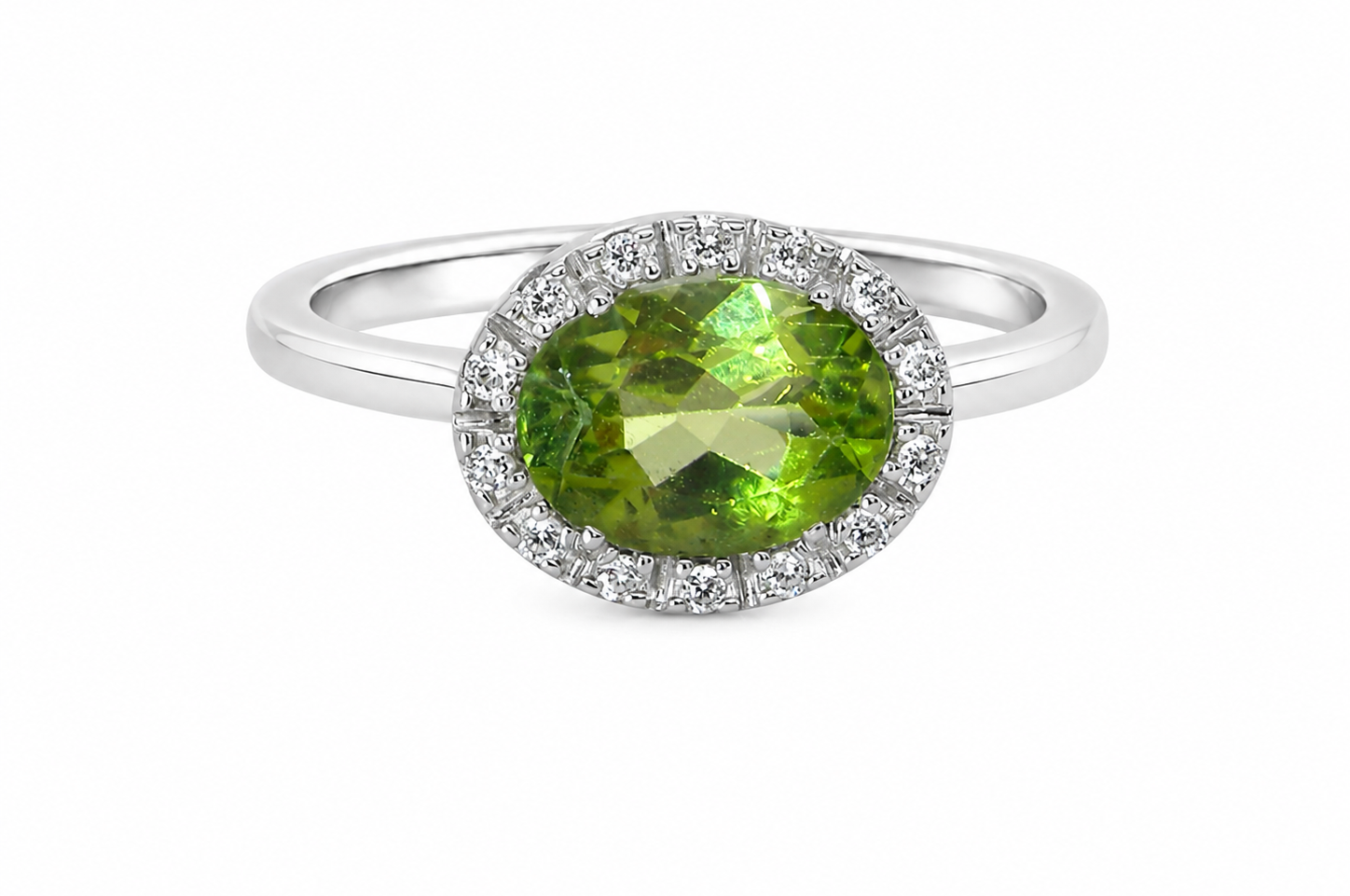 An 18 carat white gold* cluster ring. Features and oval shaped peridot gemstone, measures 8.5x6.5mm.