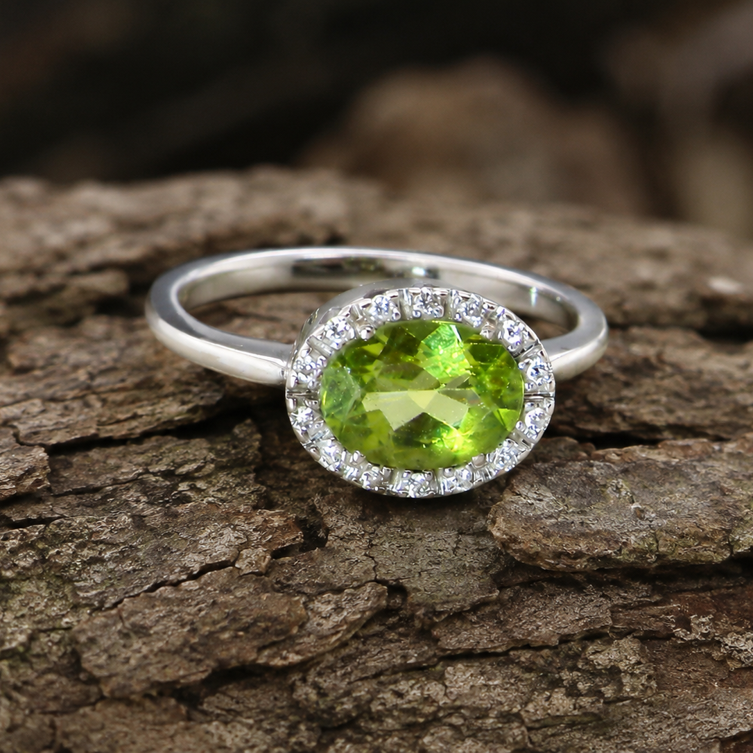 An 18 carat white gold* cluster ring. Features and oval shaped peridot measures 8.5x6.5mm.