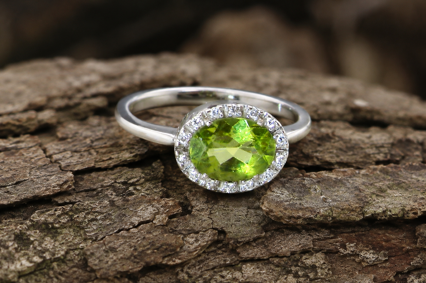 An 18 carat white gold* cluster ring. Features and oval shaped peridot measures 8.5x6.5mm.