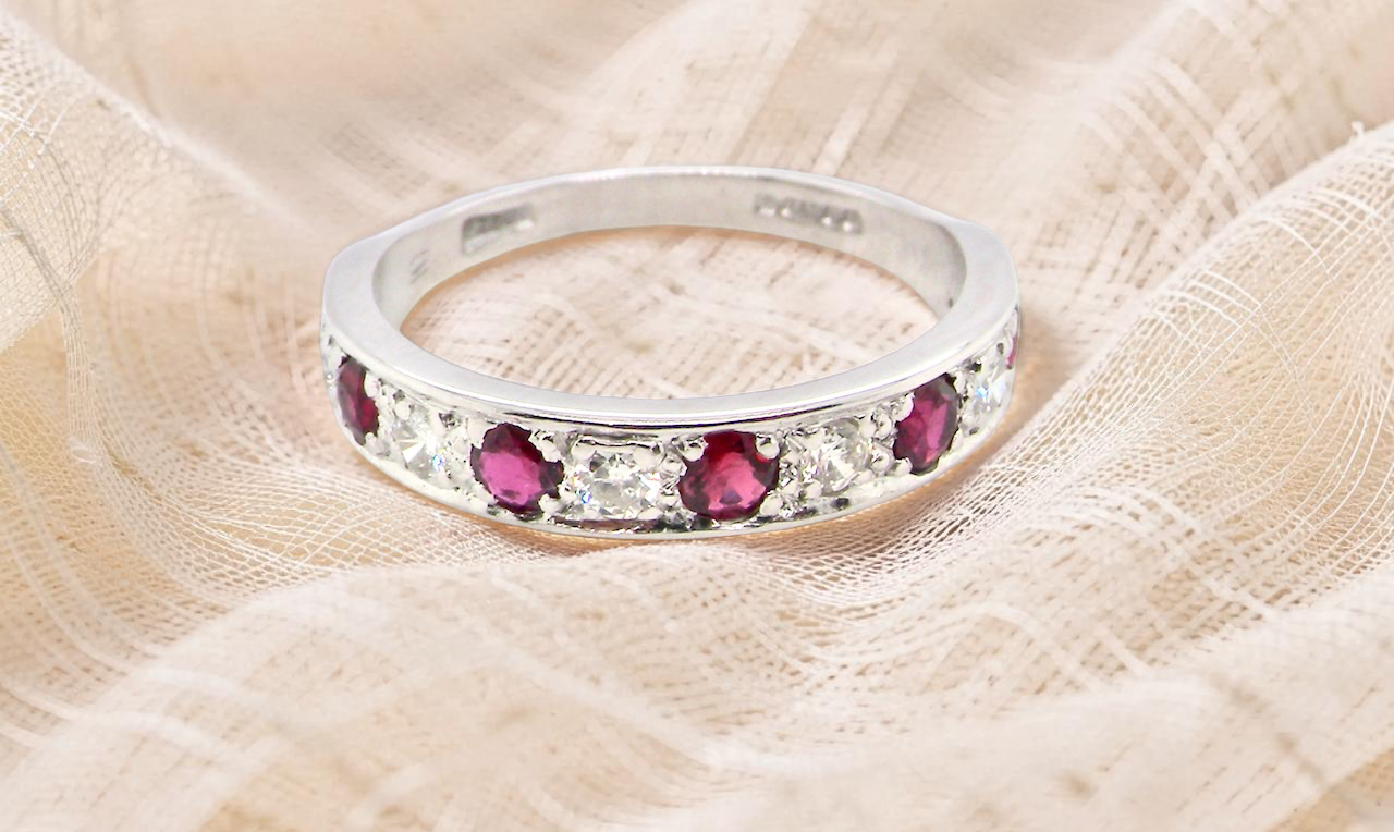 An 18 carat white gold half hoop eternity ring. Set with five round 3mm rubies 