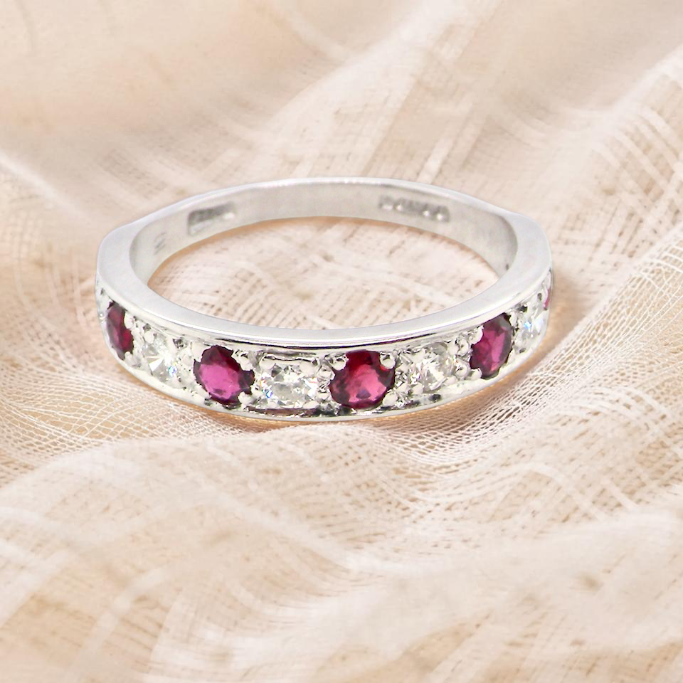 An 18 carat white gold half hoop eternity ring. Set with five round 3mm rubies 