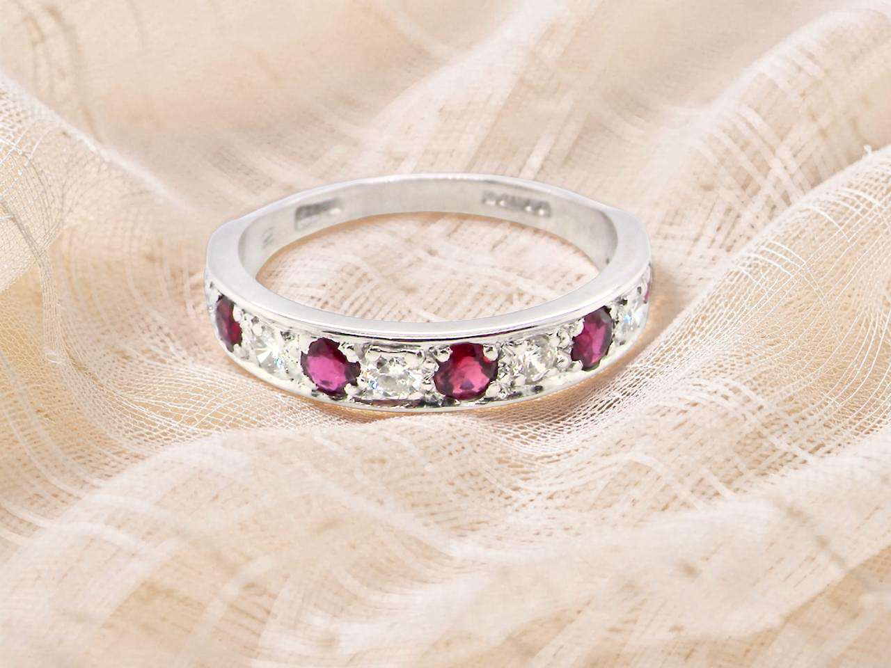 An 18 carat white gold half hoop eternity ring. Set with five round 3mm rubies 