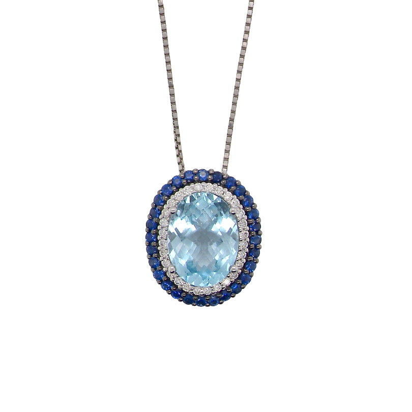 An oval pendant necklace featuring a light blue topaz center stone surrounded by a halo of silver-toned pavé diamonds and a border of deep blue sapphires, suspended from a silver-toned chain on a white background.