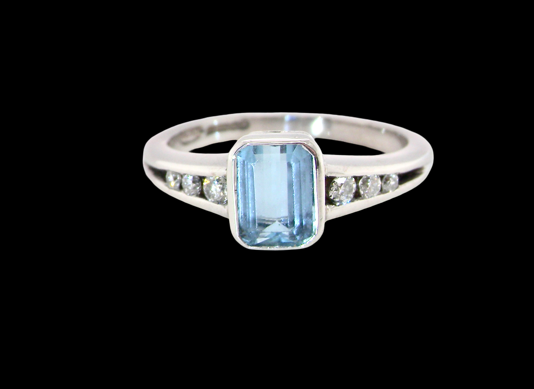 An 18 carat white gold ring, features a rectangular step cut aquamarine, measures 7x5mm (st one carat) , fine clarity. Rim setting.