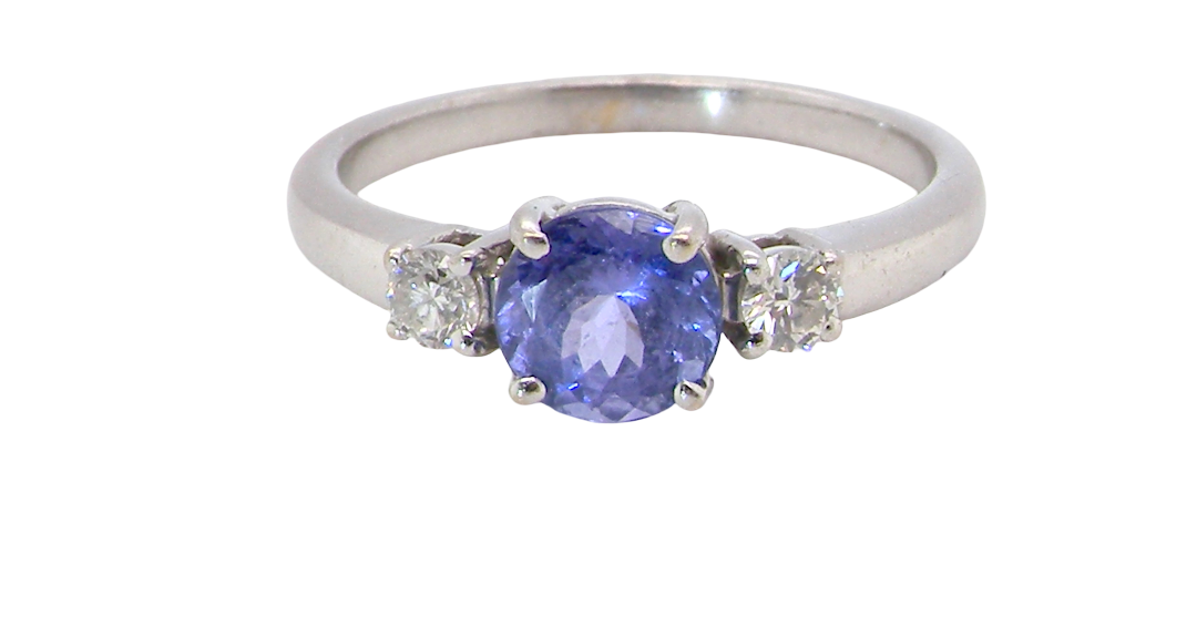 An 18 carat white gold three stone ring. Centre stone a round tanzanite
Each side a brilliant cut white diamond