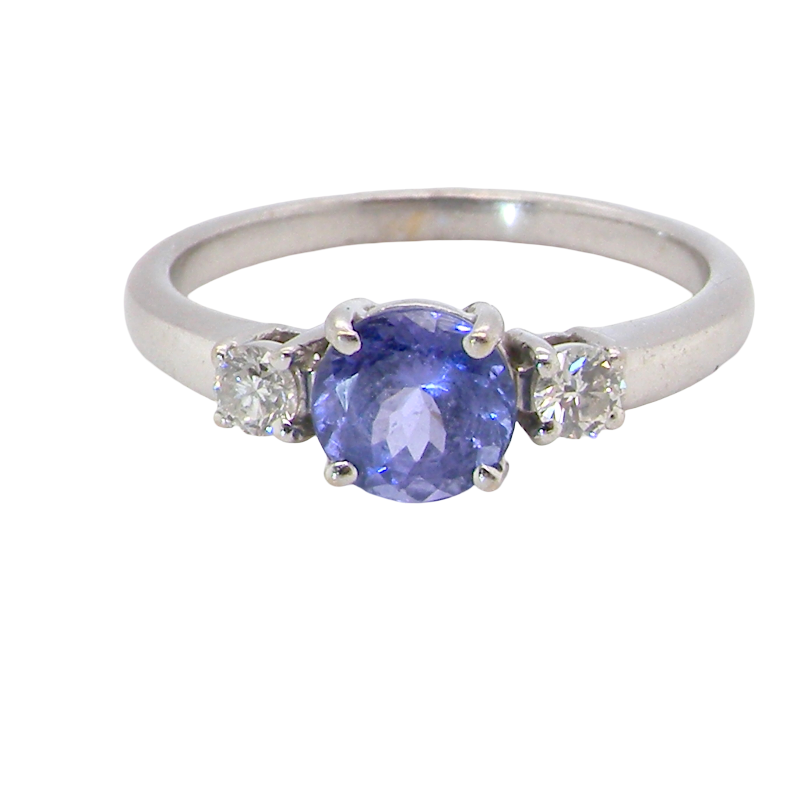 An 18 carat white gold three stone ring. Centre stone a round tanzanite
Each side a brilliant cut white diamond