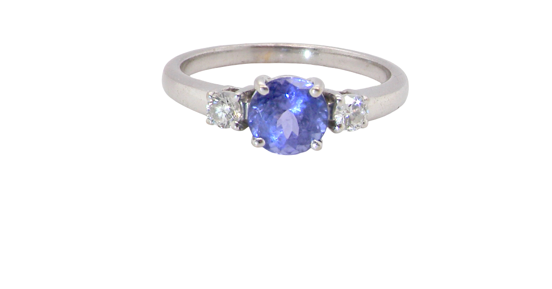 An 18 carat white gold three stone ring. Centre stone a round tanzanite 6mm diameter.
Each side a brilliant cut white diamond
