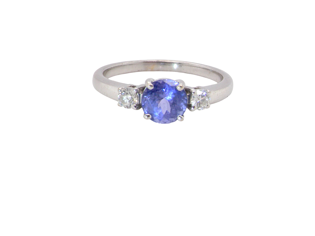 An 18 carat white gold three stone ring. Centre stone a round tanzanite 6mm diameter.
Each side a brilliant cut white diamond