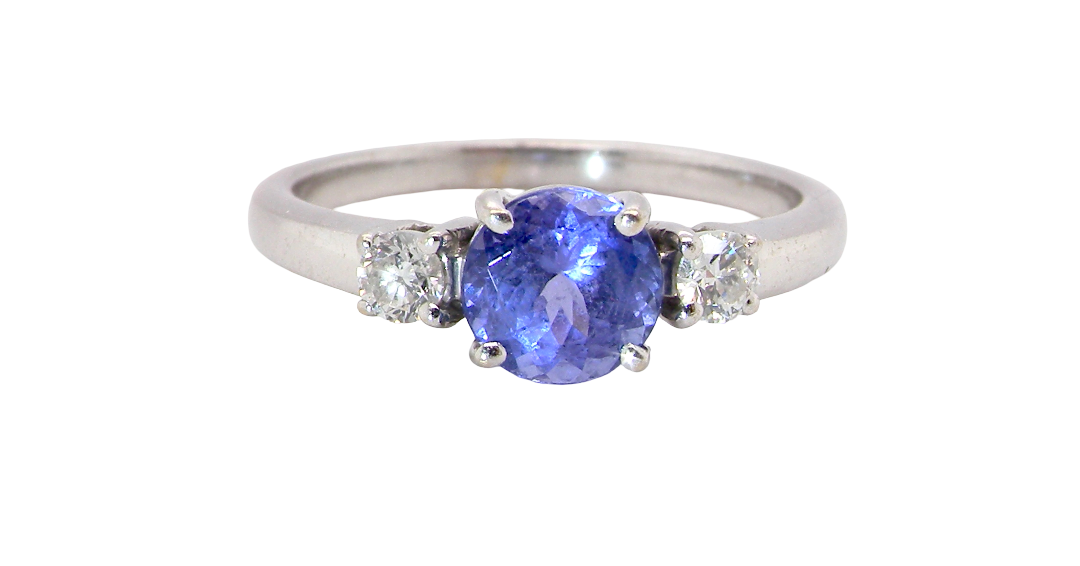 An 18 carat white gold three stone ring. Centre stone a round tanzanite 6mm diameter.
Each side a white diamond