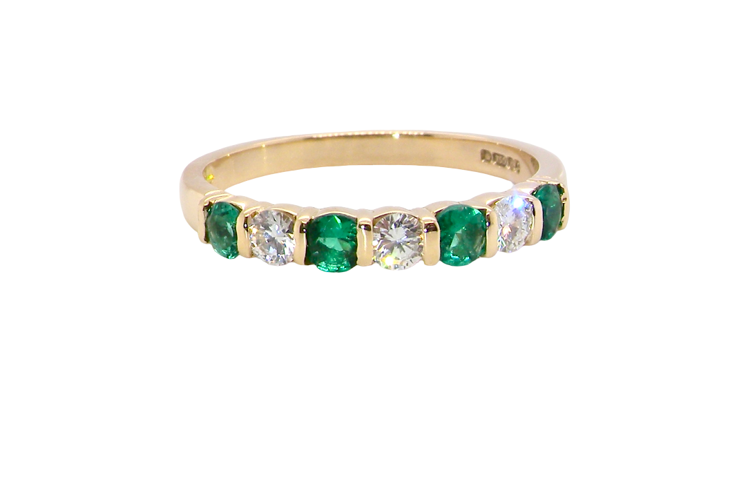 An 18 carat yellow gold half hoop eternity ring. Set with four bright green emeralds, each 3mm diameter .