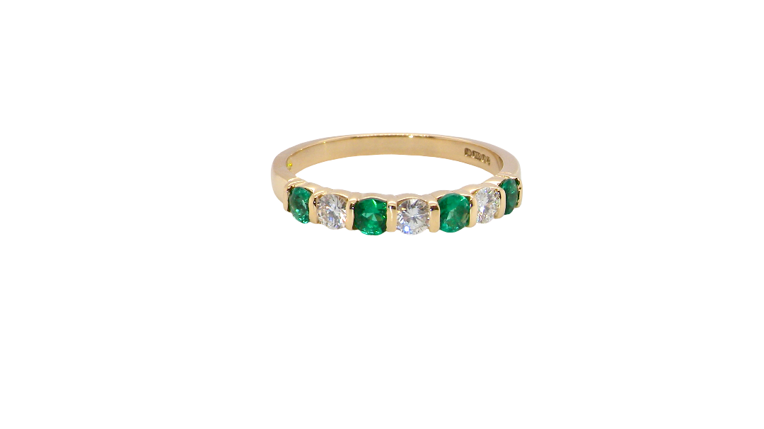 An 18 carat yellow gold half hoop eternity ring. Set with four bright green emeralds, each 3mm diameter (est each 0.10 carats) .