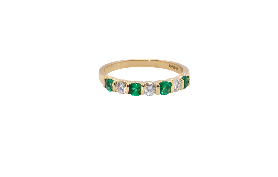 An 18 carat yellow gold half hoop eternity ring. Set with four bright green emeralds, each 3mm diameter (est each 0.10 carats) .