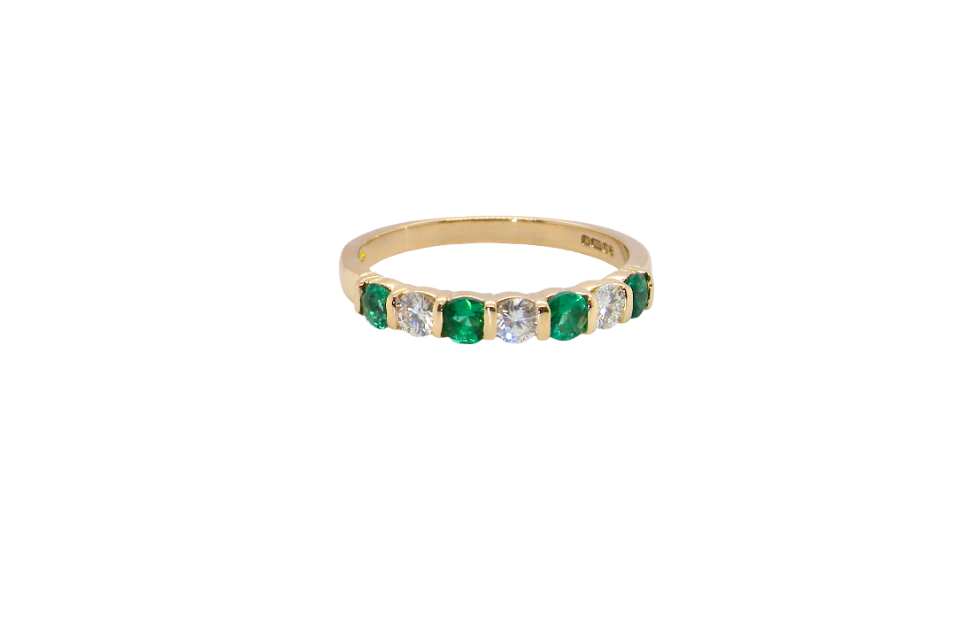 An 18 carat yellow gold half hoop eternity ring. Set with four bright green emeralds, each 3mm diameter (est each 0.10 carats) .