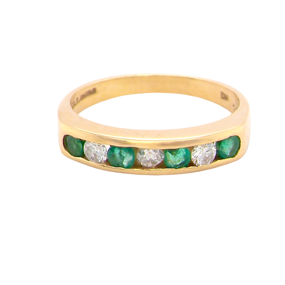 An 18 carat yellow gold half hoop eternity ring. Set with four round emeralds, each 3mm, and alternate set with brilliant cut white diamonds, each 3mm