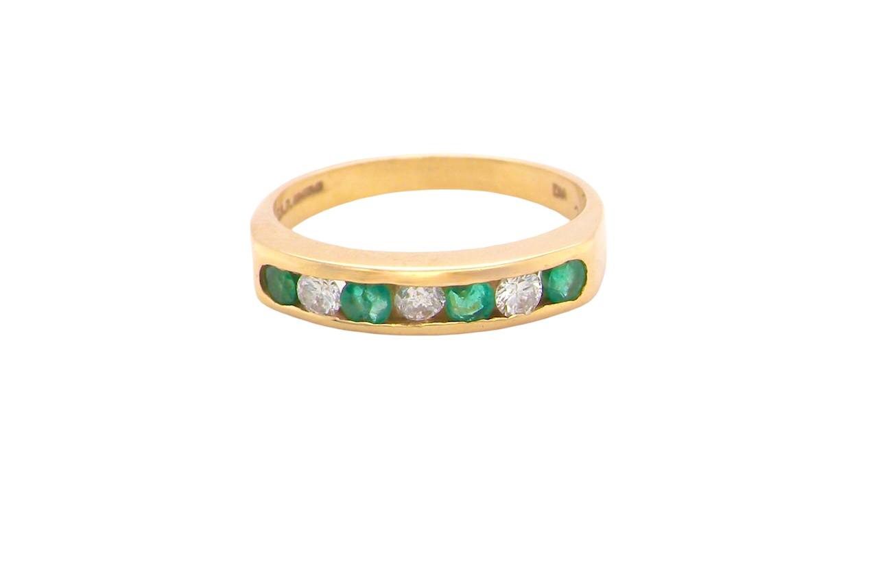 An 18 carat yellow gold half hoop eternity ring. Set with four round emeralds, each 3mm, and alternate set with brilliant cut white diamonds, each 3mm (total est 0.30 carats)