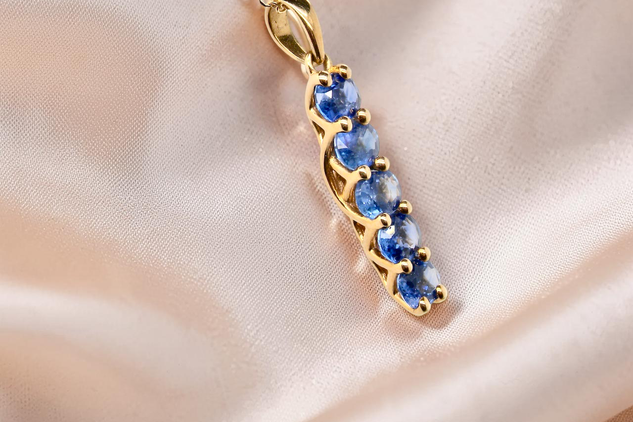 An 18 carat yellow gold pendant. This features five oval cut sapphires, each 5x3.5mm. 