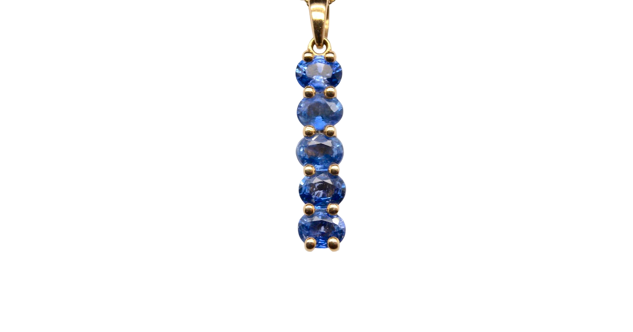 An 18 carat yellow gold pendant. This features five oval cut mid cornflower blue sapphires,