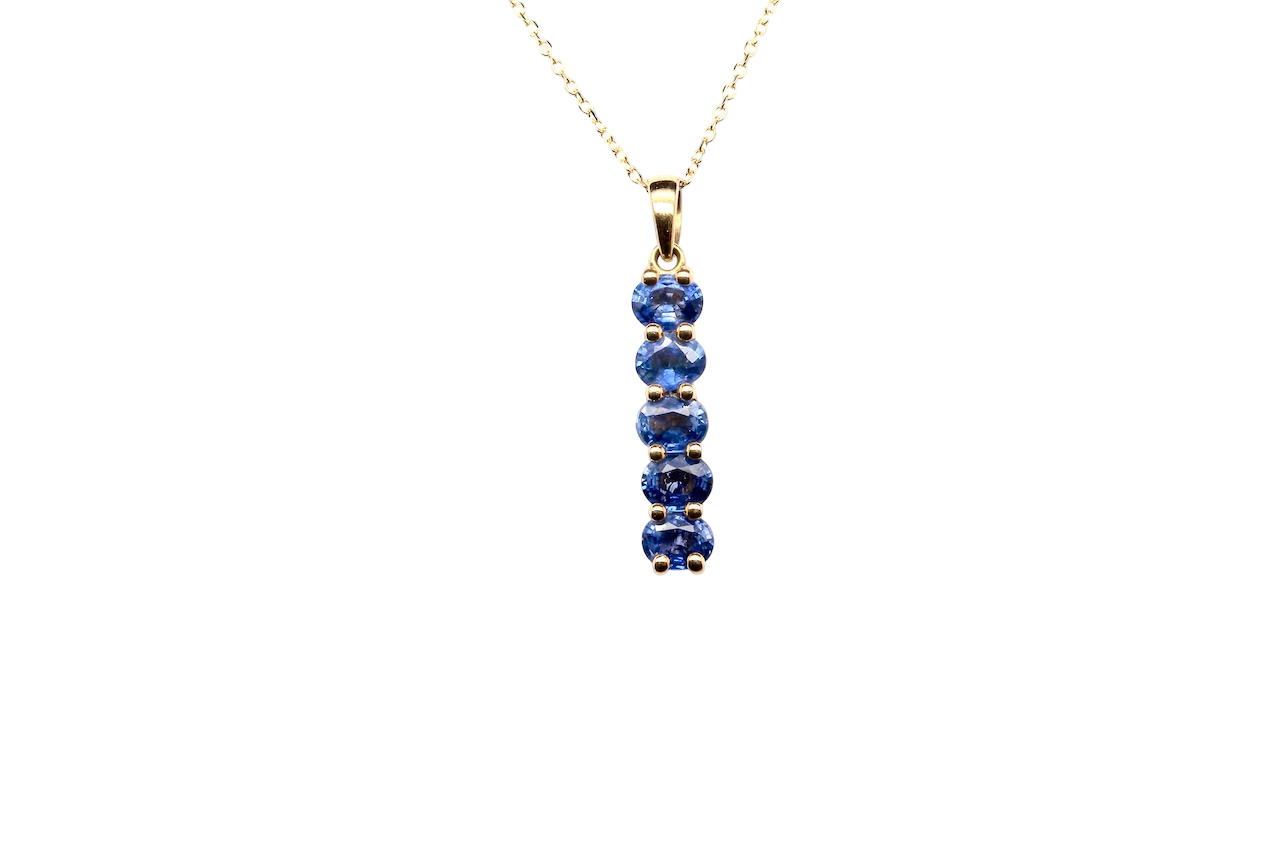 An 18 carat yellow gold pendant. This features five oval cut mid cornflower blue sapphires, each 5x3.5mm. 