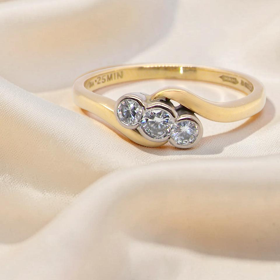 An 18 carat yellow gold three stone ring, cross over style, and set with brilliant cut white diamonds.
Centre stone 3mm