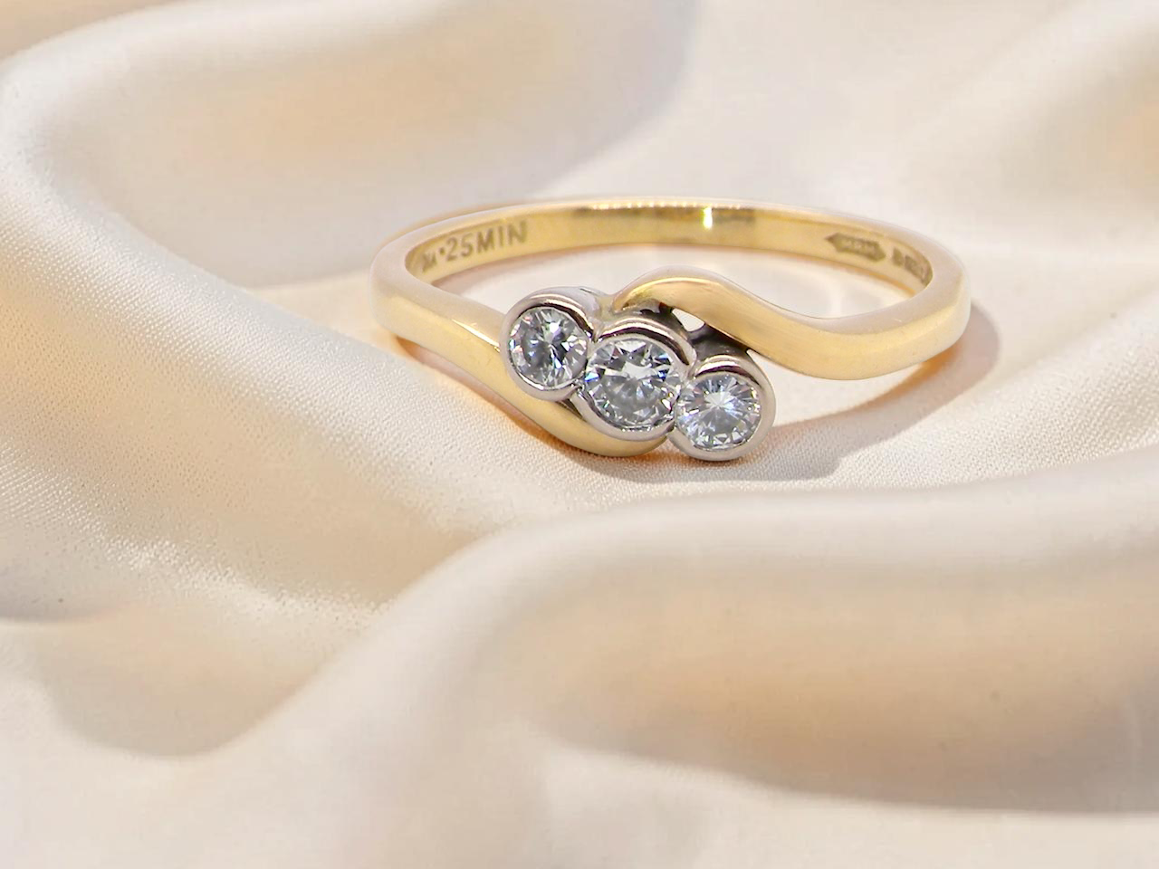 An 18 carat yellow gold three stone ring, cross over style, and set with brilliant cut white diamonds.
Centre stone 3mm