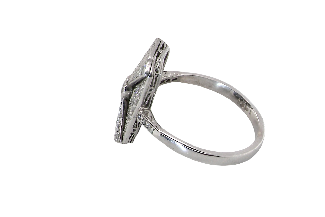 An Art Deco panel shaped cluster ring. The head measures 16x10mm, depth 3.4mm, and has two fan shaped designs that feature above and below a brilliant cut white diamond centre stone which measures 3.4mm (0.15 carats est)
side